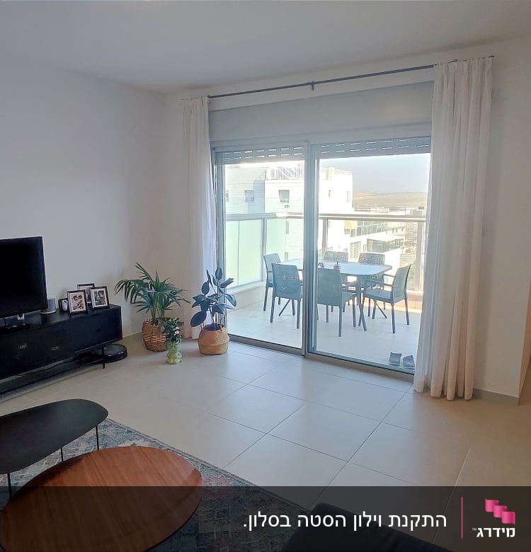 וילון לבן תלוי על חלון זכוכית גדול